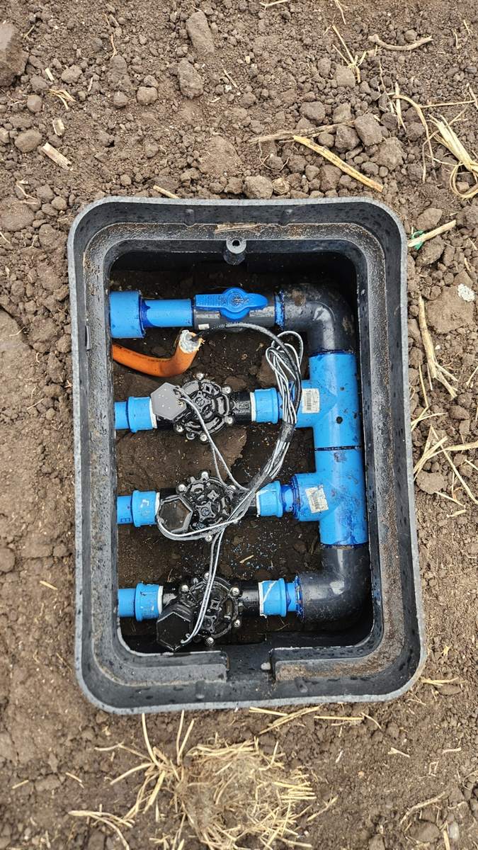 Cámara de válvulas de riego automático instalada, con las electroválvulas y conexiones a la vista