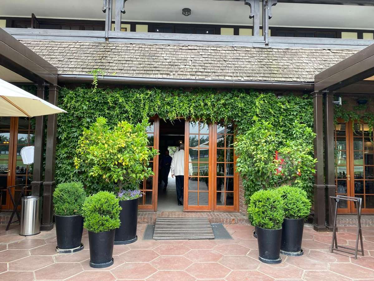 Acceso del Club de Polo y Equitación San Cristóbal con maceteros y topiarios a ambos lados