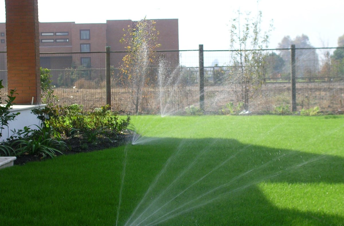 Aspersores de riego automático funcionando sobre el césped de un jardín