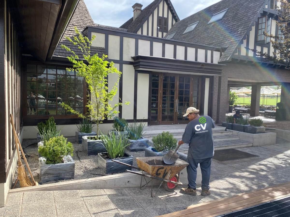 Jardinero de CV Paisajismo con polera institucional trabajando en los maceteros del Club de Polo y Equitación San Cristóbal